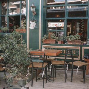 Cozy outdoor cafe seating area with plants and wooden tables, inviting natural ambiance.